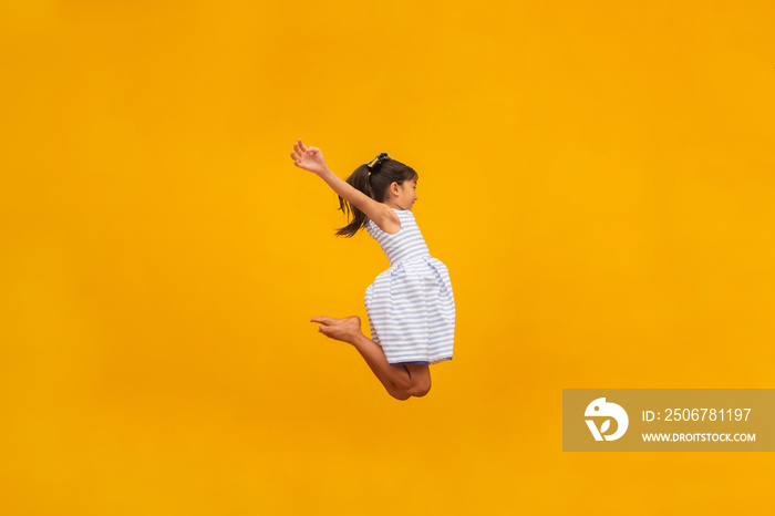 Beautiful asian girl sitting on yellow background. Happy little Asian girl smiling.