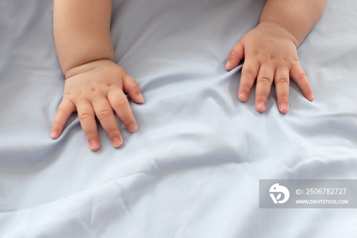 cute little baby boy hands are crawling and playing on the soft blanket at the family bedroom with c