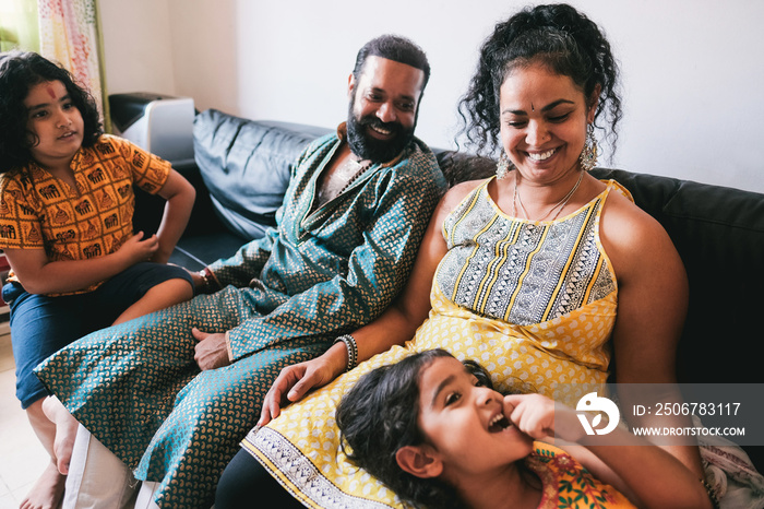 Indian family having fun at home sitting on sofa - Soft focus on mum face