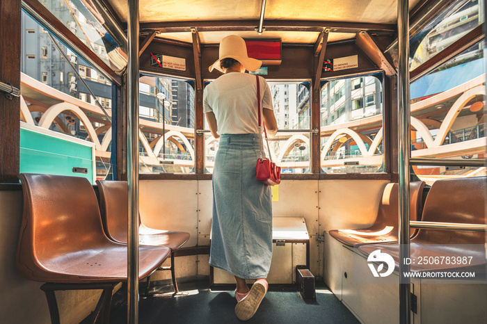 Woman wearing straw hat stand on tram in Hong Kong