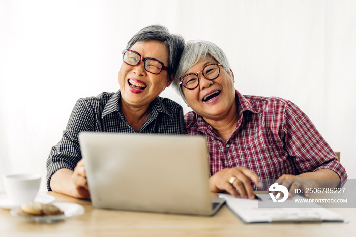 Portrait of two friend happy senior adult elderly asia women smiling and working with laptop compute