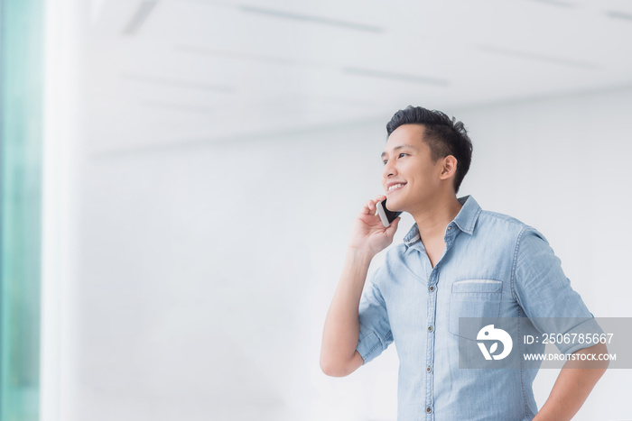 Portrait of Happy Asian man talking on a smartphone in building with copyspace