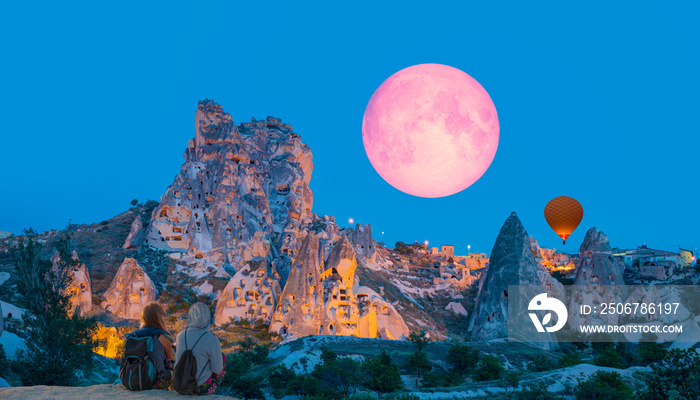 黄昏蓝色时刻，卡帕多西亚乌奇萨城堡的壮丽景色-女孩们在看月亮升起
