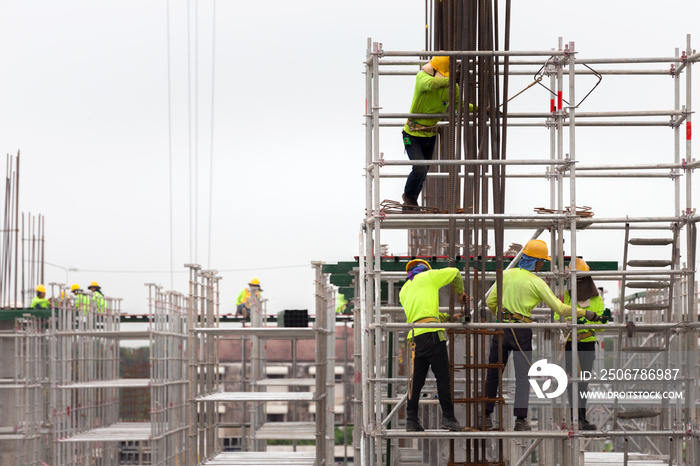 asian construction workers working on scaffolding of building construction site in city. urban expan