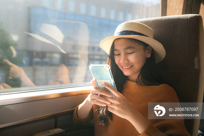 Young asian woman traveler using smartphone in train. Girl traveler smiling holding mobile phone tex