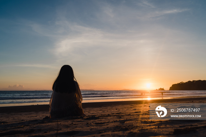 Young Asian woman watching sunset near beach, beautiful female happy relax enjoy moment when sunset 