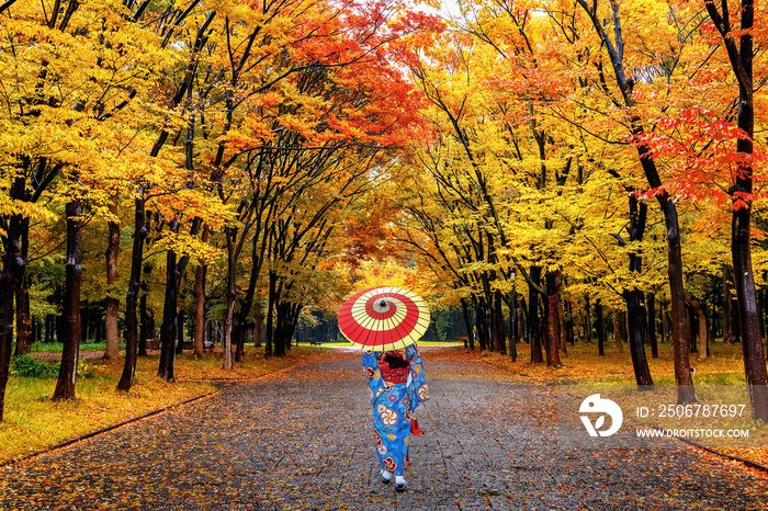 Asian woman wearing japanese traditional kimono walking in autumn park.