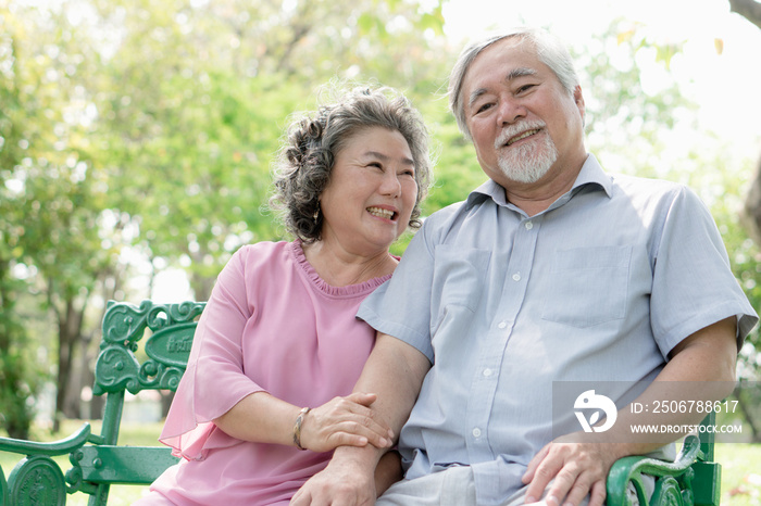 Asian healthy senior couple relaxing seated in the park together.