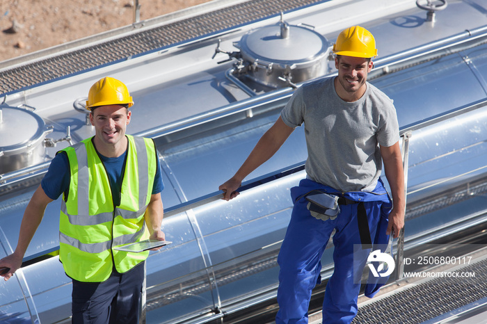 Portrait confident male workers above milk tanker