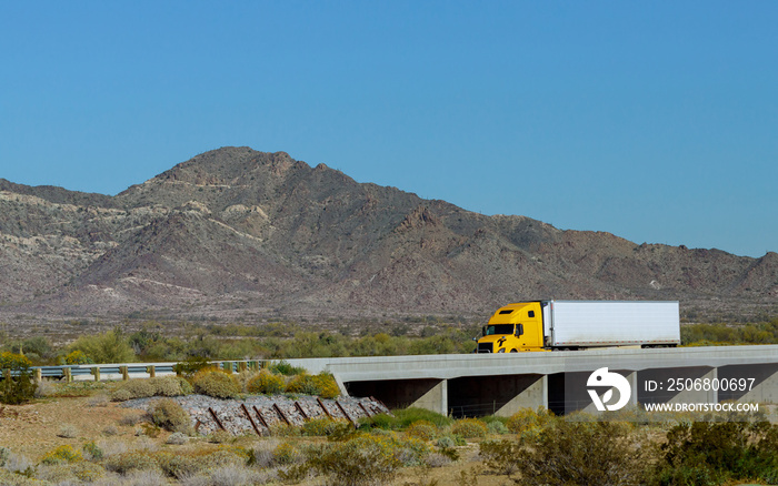 Big rig long haul semi truck with two flat bed semi trailers transporting on the winding road with b