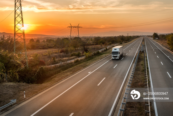 Single White lorry truck on a country highway under amazing orange sunset sky