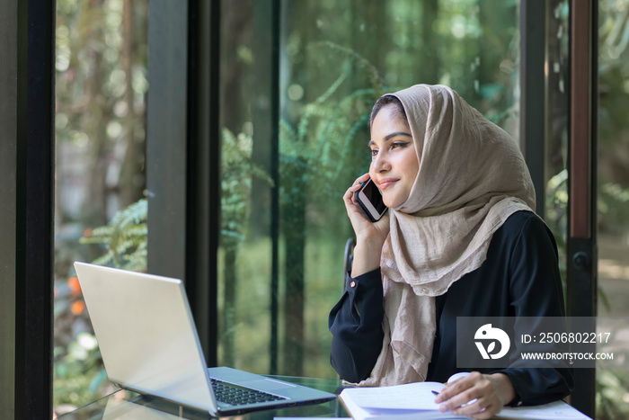 一位穆斯林女士在办公桌上忙着打电话。