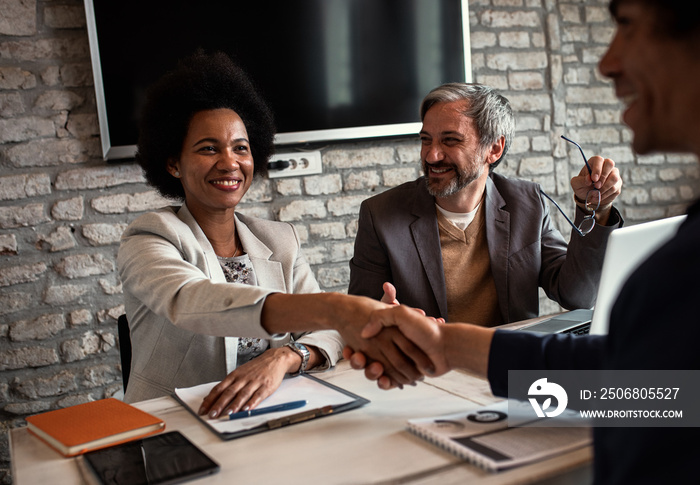 Business recruiters shakes hands with candidate during job interview.