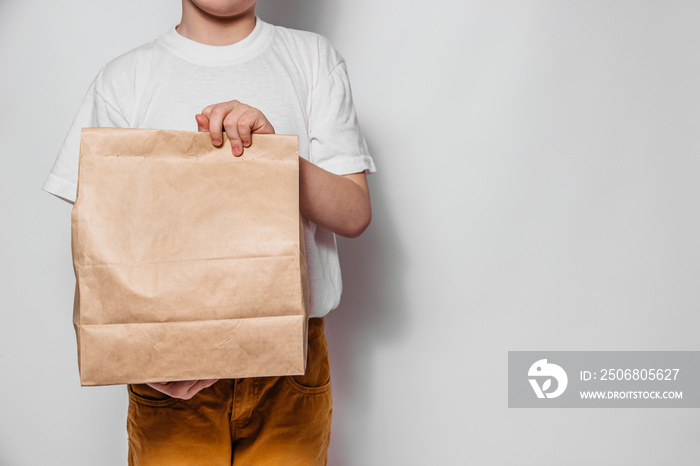 The courier guy holds in his hands a brown craft paper bag for the removal or delivery of goods and 