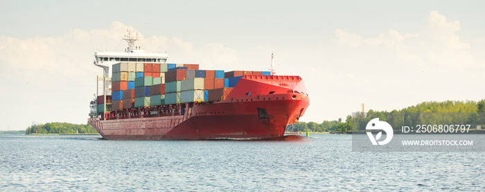 Container ship (168 meters length) leaving port terminal at sunset. Baltic sea. Freight transportati