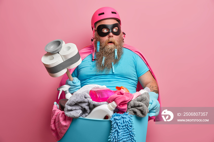 Shocked bearded plump man janitor in superhero costume looks after children and does cleaning at sam