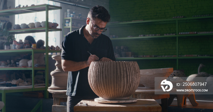 Potter creating ornament on clay bowl