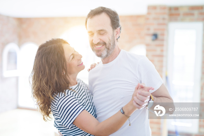 Middle age senior couple moving to a new house, dancing and smiling happy in love with apartmant