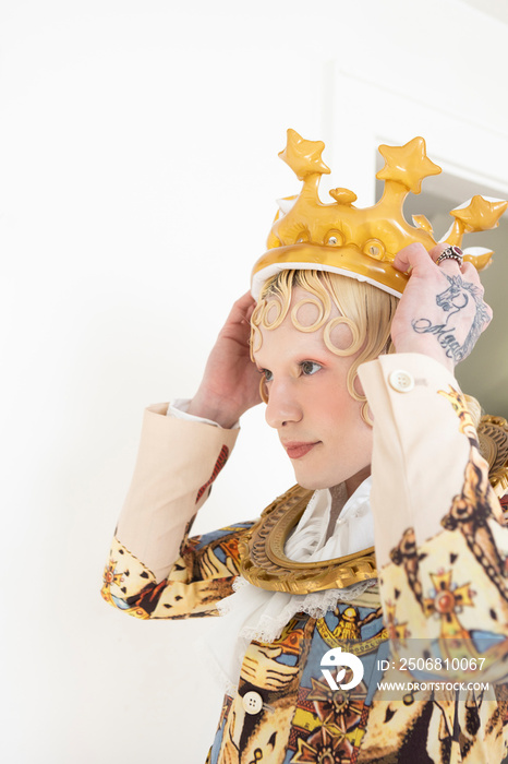 non-binary hispanic person with blonde hair putting on inflatable crown