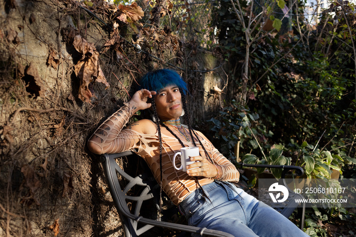 indigenous non-binary artist drinking tea in urban garden in autumn