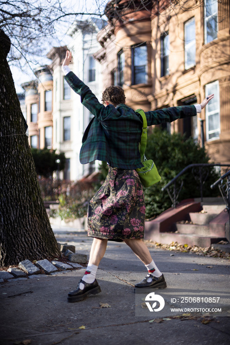 non-binary caucasian person with short hair dancing on Brooklyn sidewalk