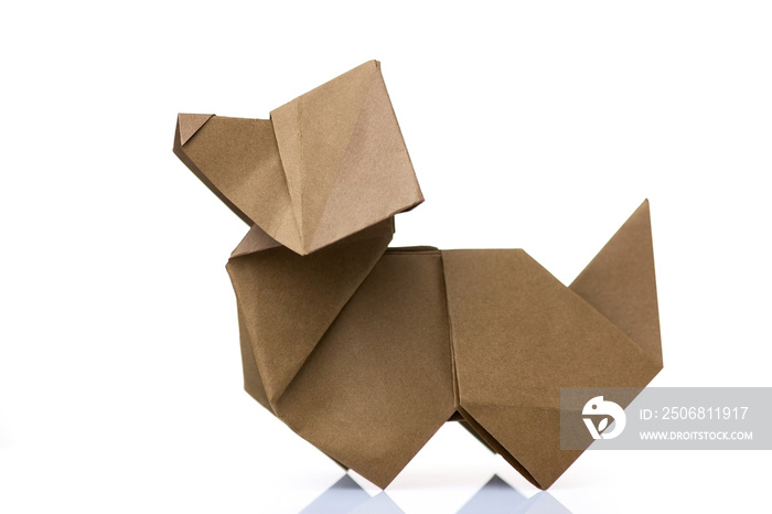 Origami dog on white background. Simplified design of paper animal. Result of hand crafting of littl