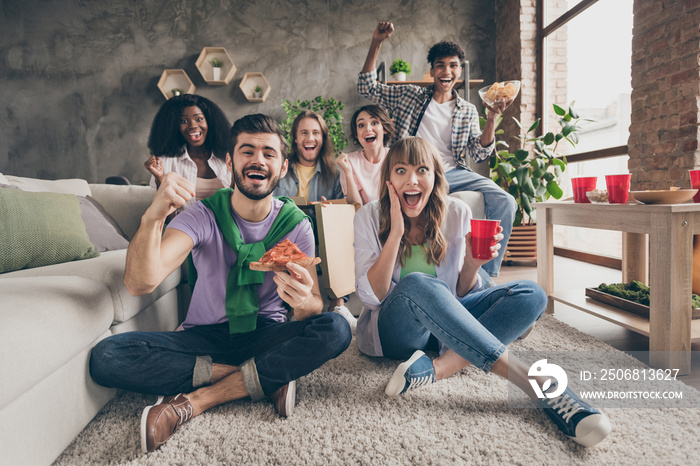 Portrait of nice amazed cheerful friends sitting on carpet having fun eating snack watching cinema l