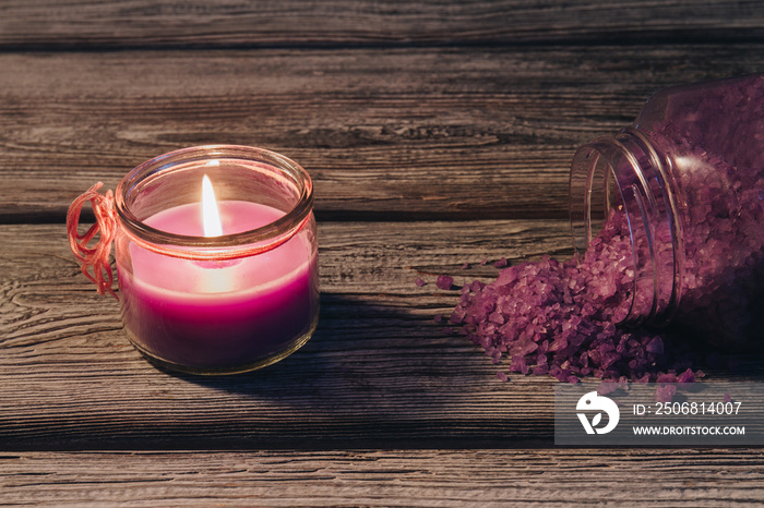 Concept spa therapy. Burning candle and sprinkled salt from a can on wooden table.