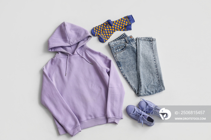 Stylish lilac hoodie with socks, jeans and sneakers on light background