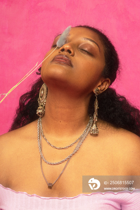 Malaysian Indian individual laughing and posing in a studio setting with a pink background