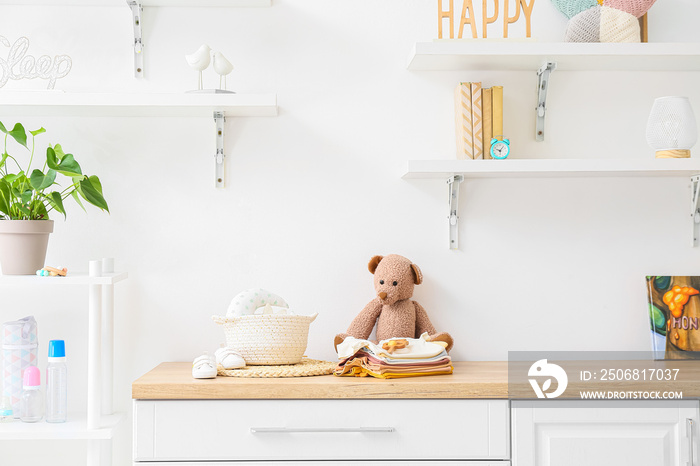 Baby clothes, shoes and toys on chest of drawers in childrens room