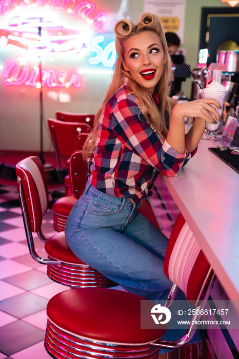 Photo of gorgeous cheerful woman drinking milkshake and smiling