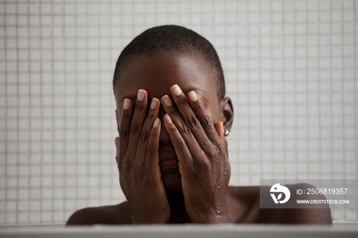 Woman in bathroom with hands covering her face