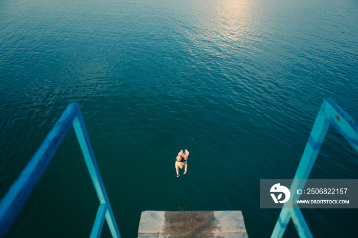 man jumping from tower at lake water on sunset