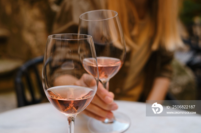 A glass of rose wine in the hands of a girl relaxing on restaurant terrace. Summer holiday. Celebrat