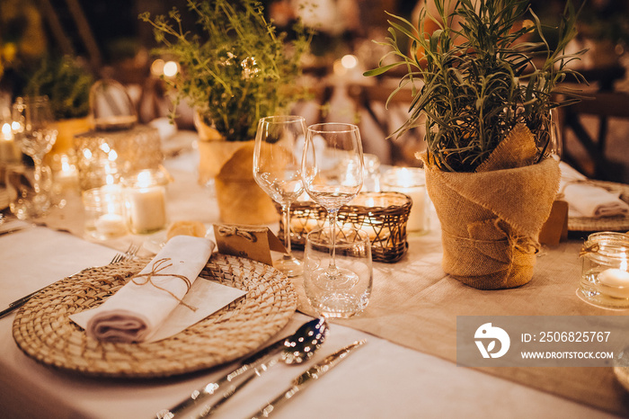 婚宴区的节日餐桌上有盘子、玻璃杯、蜡烛、餐具，桌子是装饰品
