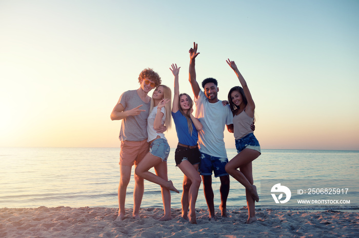 Group of happy friends having fun at ocean beach at dawn