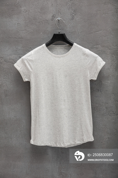 衣架上的女性灰色混杂棉质t恤的正面，背景是混凝土墙。