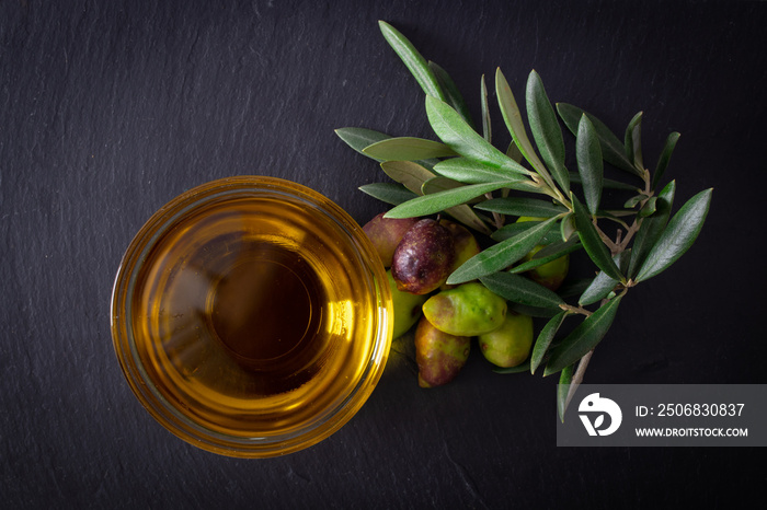 glass vessel with extra virgin olive oil and natural olives with olive branches