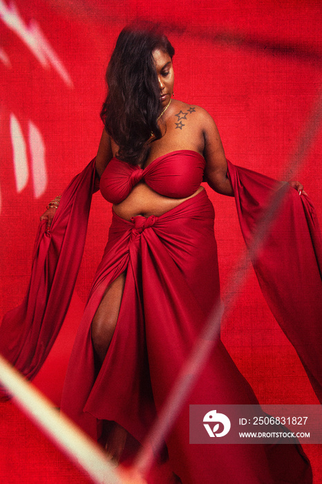 Malaysian Indian individual dressed in red clothing, against a red background, posing and laughing