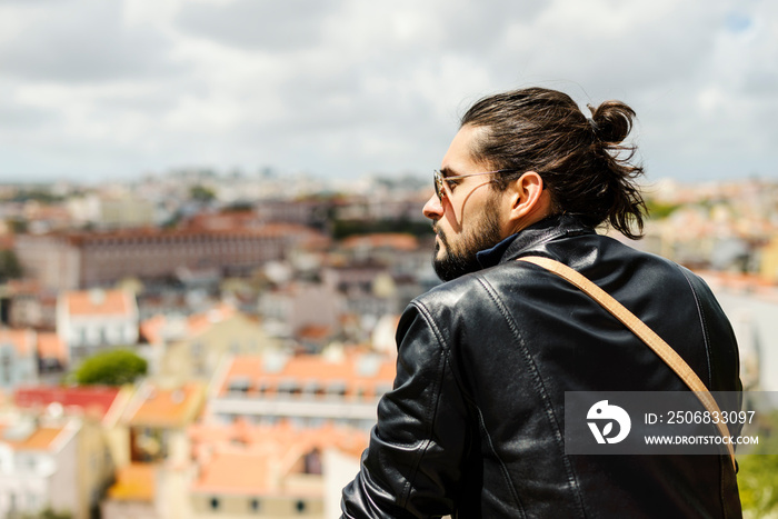 Young bearded and long haired man wearing leather jacket and sunglases walking on the southern europ