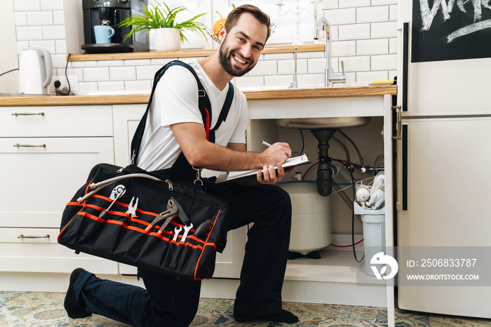 Image of plumber man with equipment and clipboard working in apartment