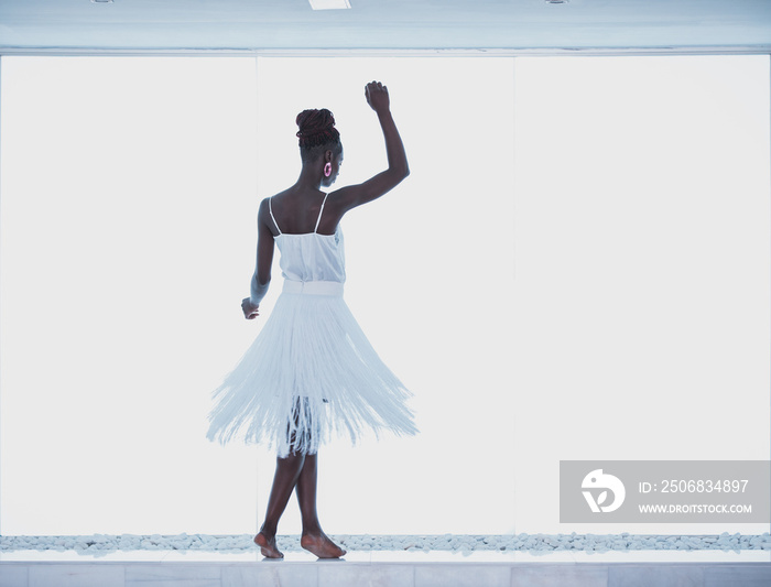 Attractive black woman wearing white fringed dress dancing on a dance floor