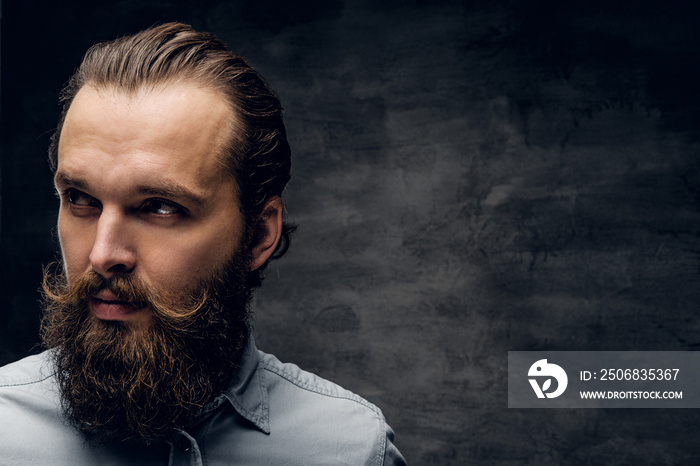 Groomed bearded man in light shirt is posing at dark photo studio.