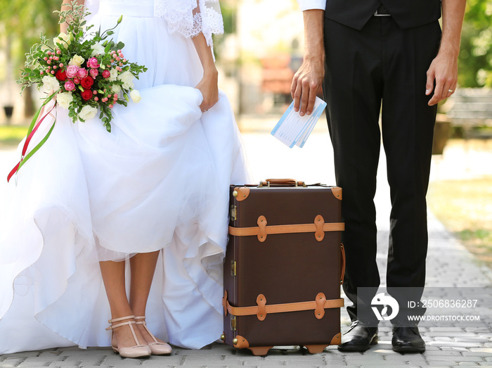 新郎和新娘带着复古行李箱在公园的小路上