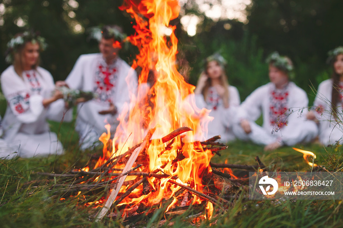 仲夏。穿着斯拉夫服装的年轻人坐在炉火旁的树林里。