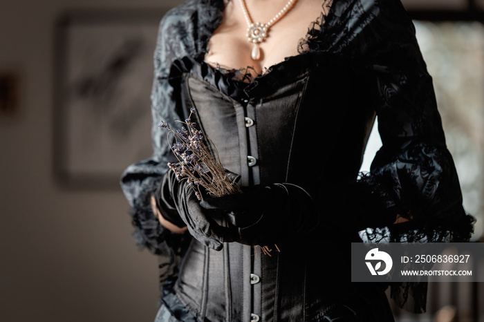 Beautiful woman in vintage black dress holding a dry lavender flowers