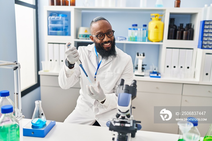 Young african american man wearing scientist uniform using pipette at laboratory