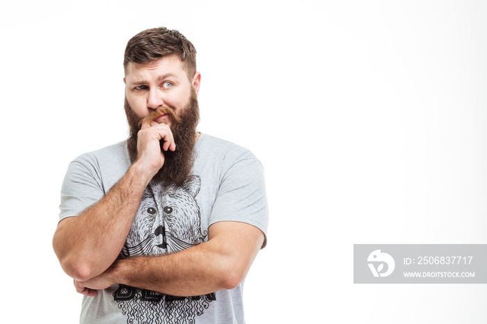 Pensive handsome bearded man standing with hands folded and thinking