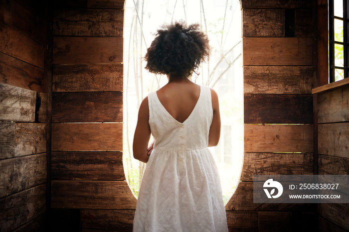 Rear view of girl looking through tree house window